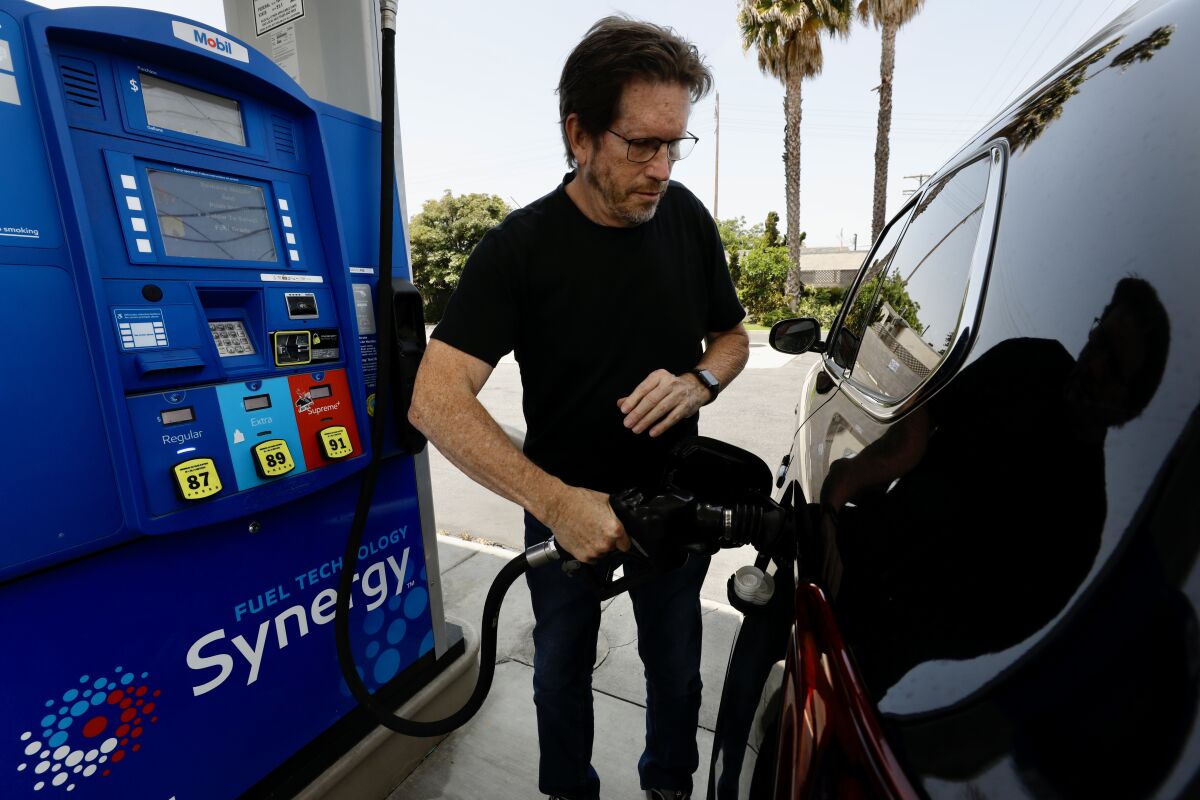 A man holds the nozzle of a gas pump as he fills his tank.