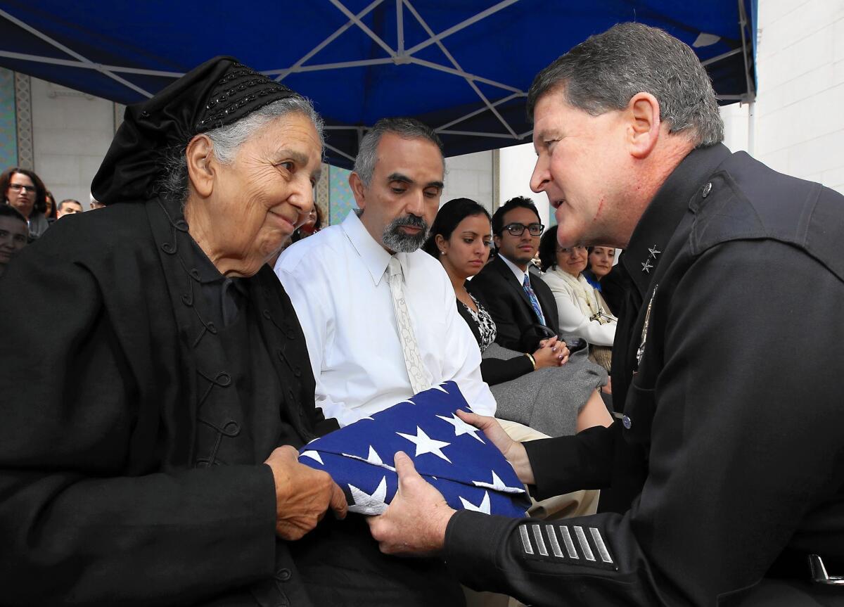 Los Angeles police Deputy Chief Michael Downing, right, presents a flag to Ragaa Hathout during a memorial service Saturday honoring her husband, Maher Hathout, who died Jan. 3. He was widely known as a champion of moderate Islam and peace with other religions.
