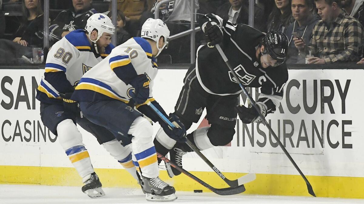Kings center Anze Kopitar, right, trips as he competes for the puck with St. Louis' Ryan O'Reilly, left, and Brayden Schenn on March 7 at Staples Center.