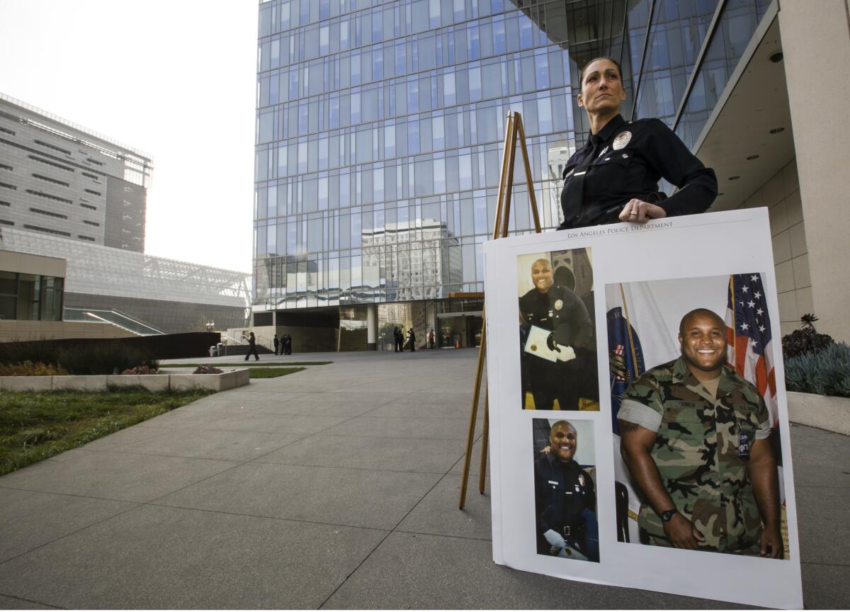 A woman stands outside LAPD headquarters with a poster holding three photos.