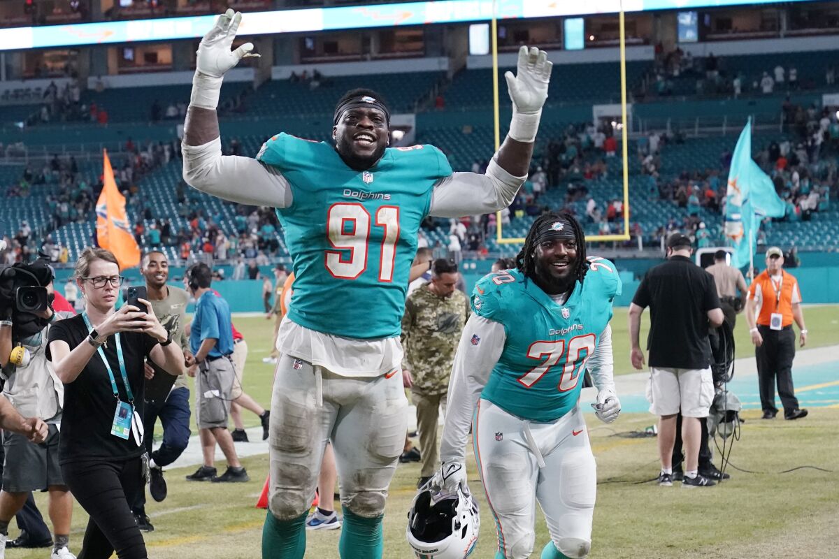 FILE - Miami Dolphins defensive end Emmanuel Ogbah (91) and nose tackle Adam Butler (70) celebrate at the end of an NFL football game against the Baltimore Ravens, Thursday, Nov. 11, 2021, in Miami Gardens, Fla. The Miami Dolphins agreed with Emmanuel Ogbah on a four-year contract and Chase Edmonds on a two-year deal on Monday, March 14, 2022. (AP Photo/Wilfredo Lee, File)