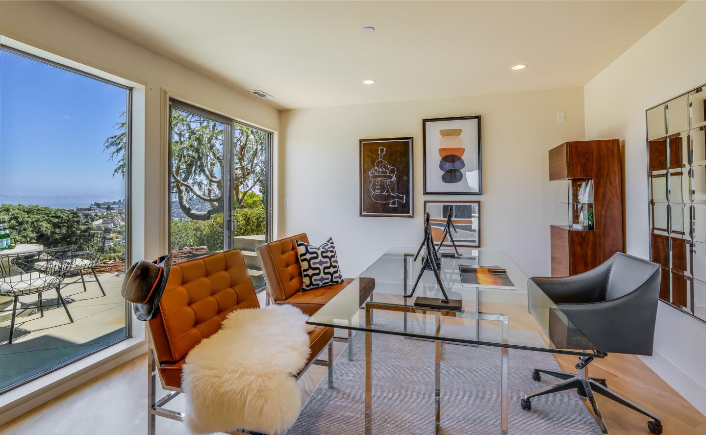 A small office with light wood floors is fronted by floor-to-ceiling windows.