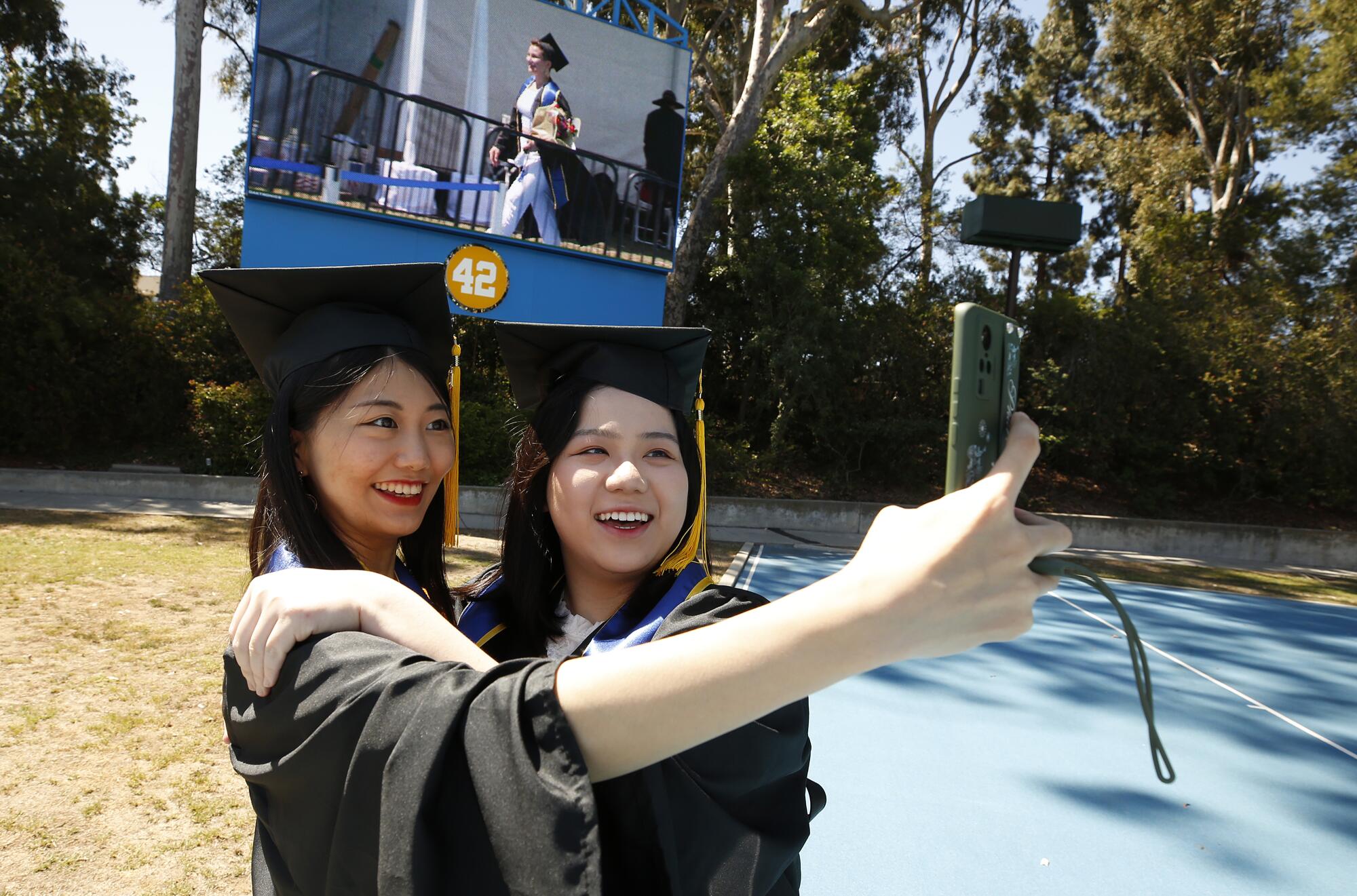 Yuying Wang, left, takes a selfie with Ziyan Wu as graduating UCLA students.