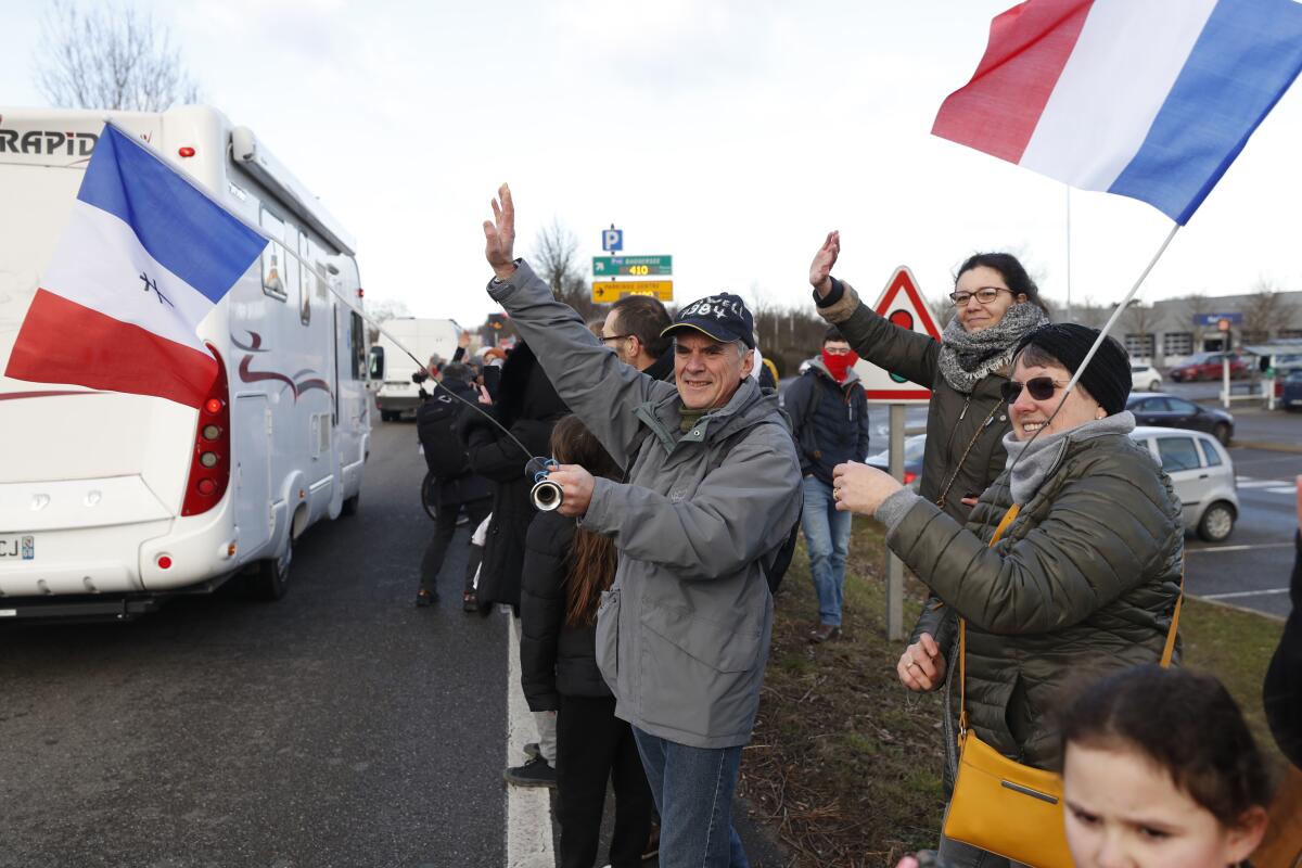 People wave to a convoy departing for Paris