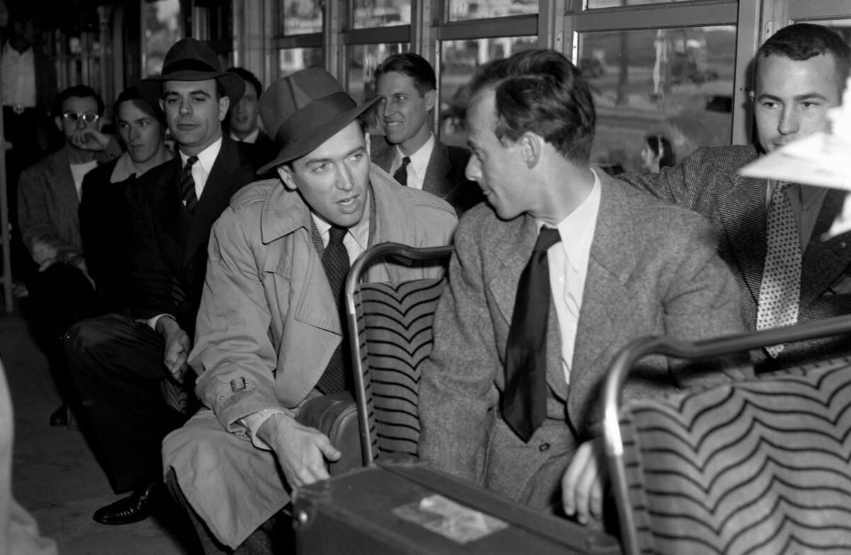 Men in suits and ties sit inside a trolley.