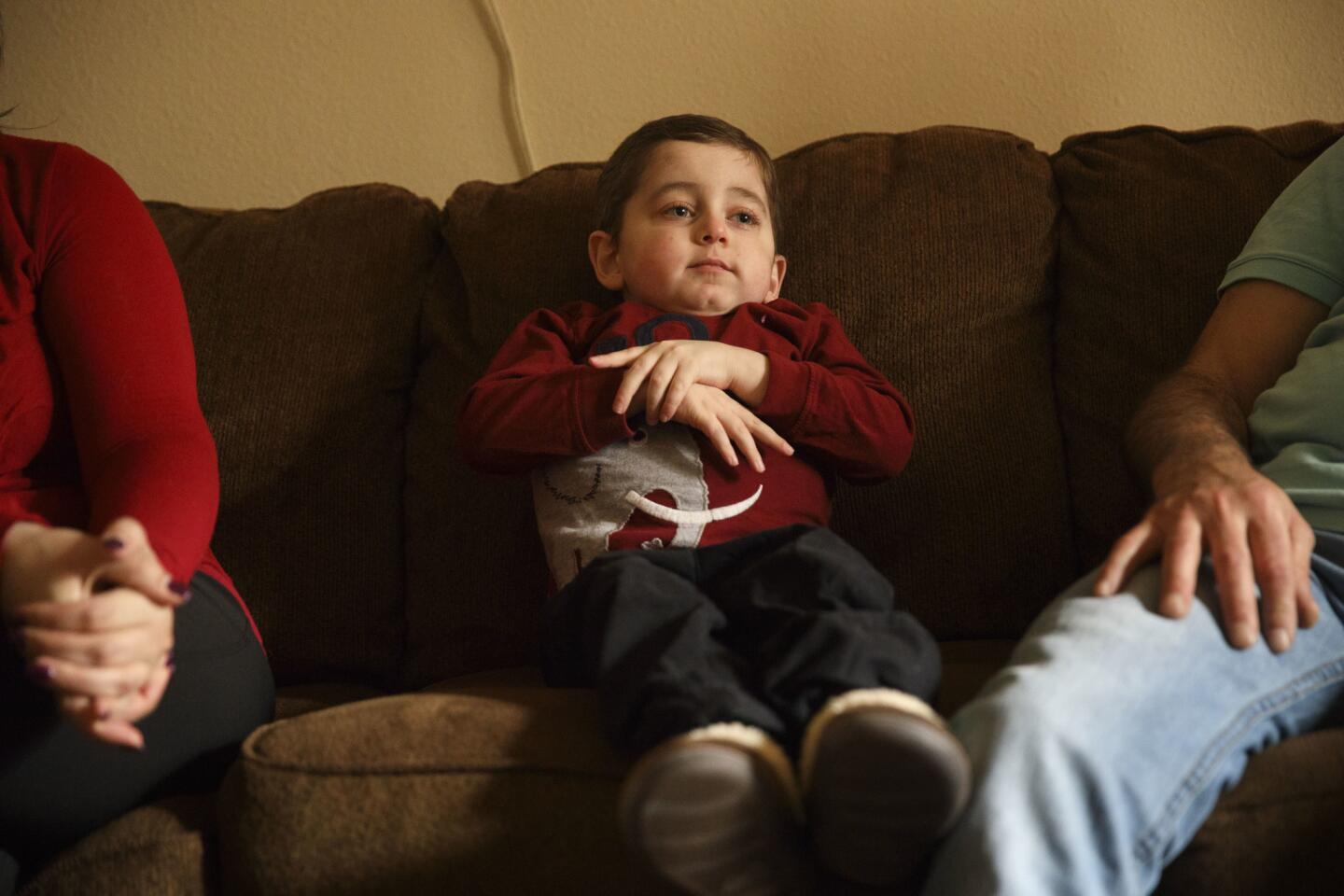 Tony Alsabaa, 5, a Syrian American boy sent to L.A. for treatment for a rare disease, sits with his aunt Fadaa Assaf and uncle Amil Rebz at their home in Santa Clarita.