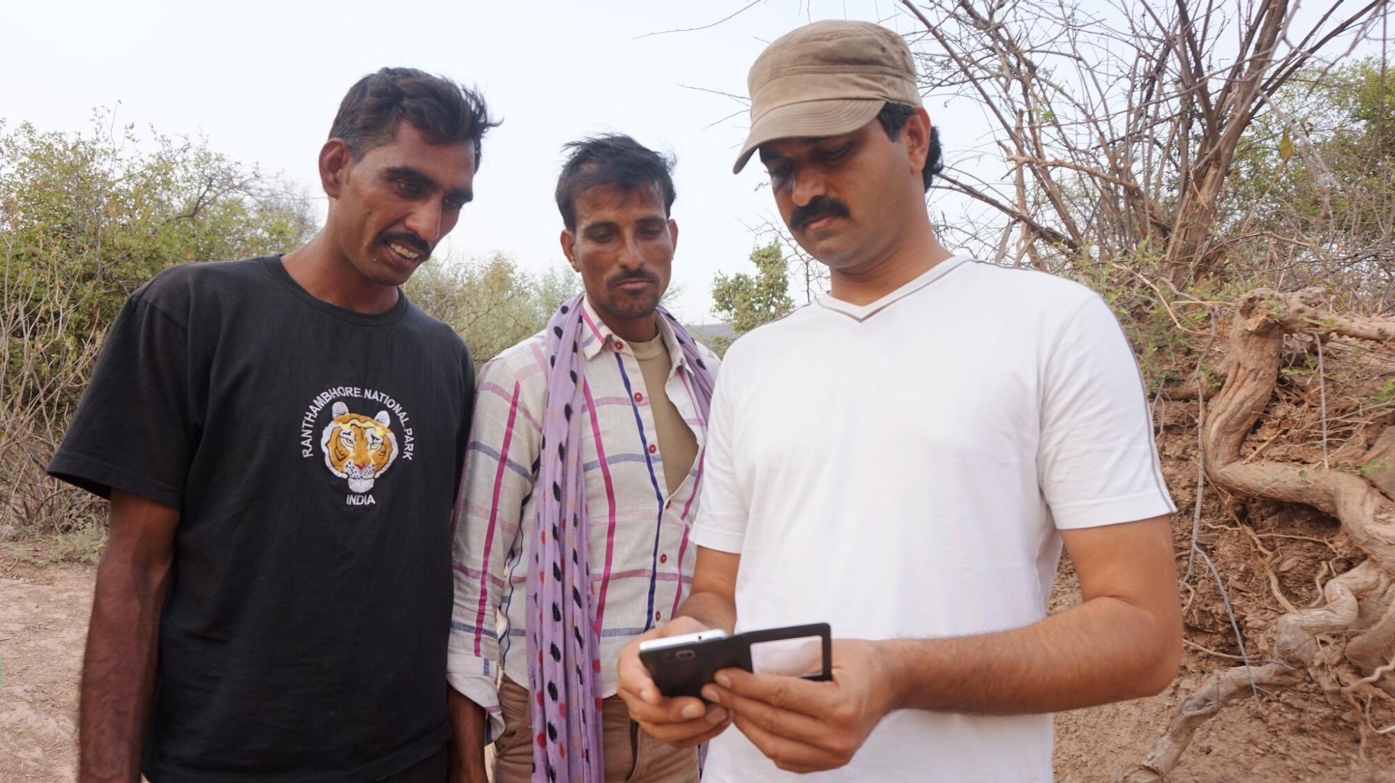 Dharmendra Khandal, right, reviews images with two village wildlife trackers outside Ranthambore.