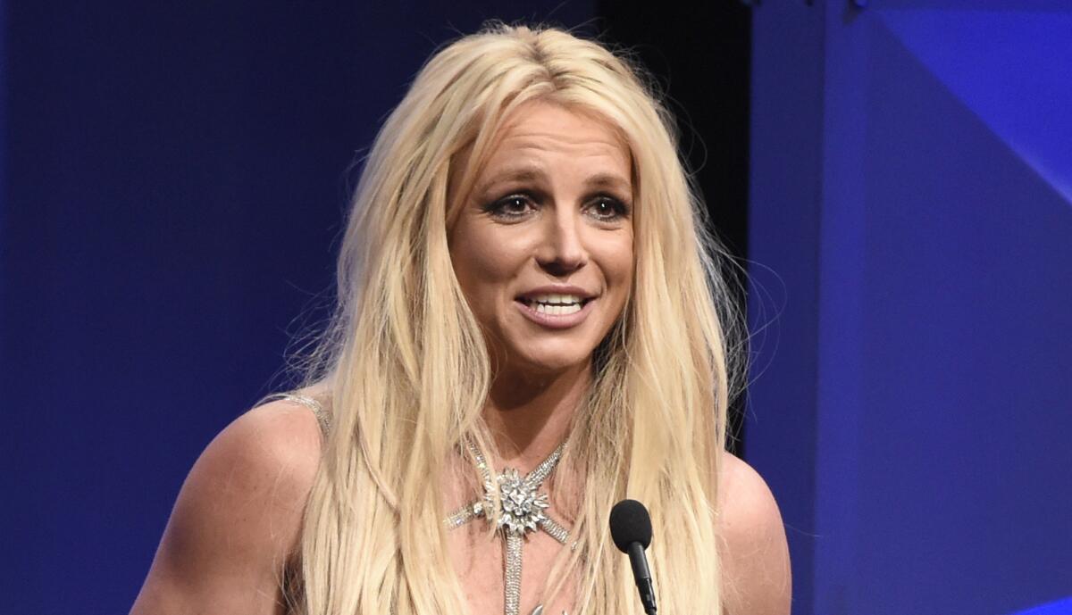 Britney Spears leans in to speak into a standing microphone