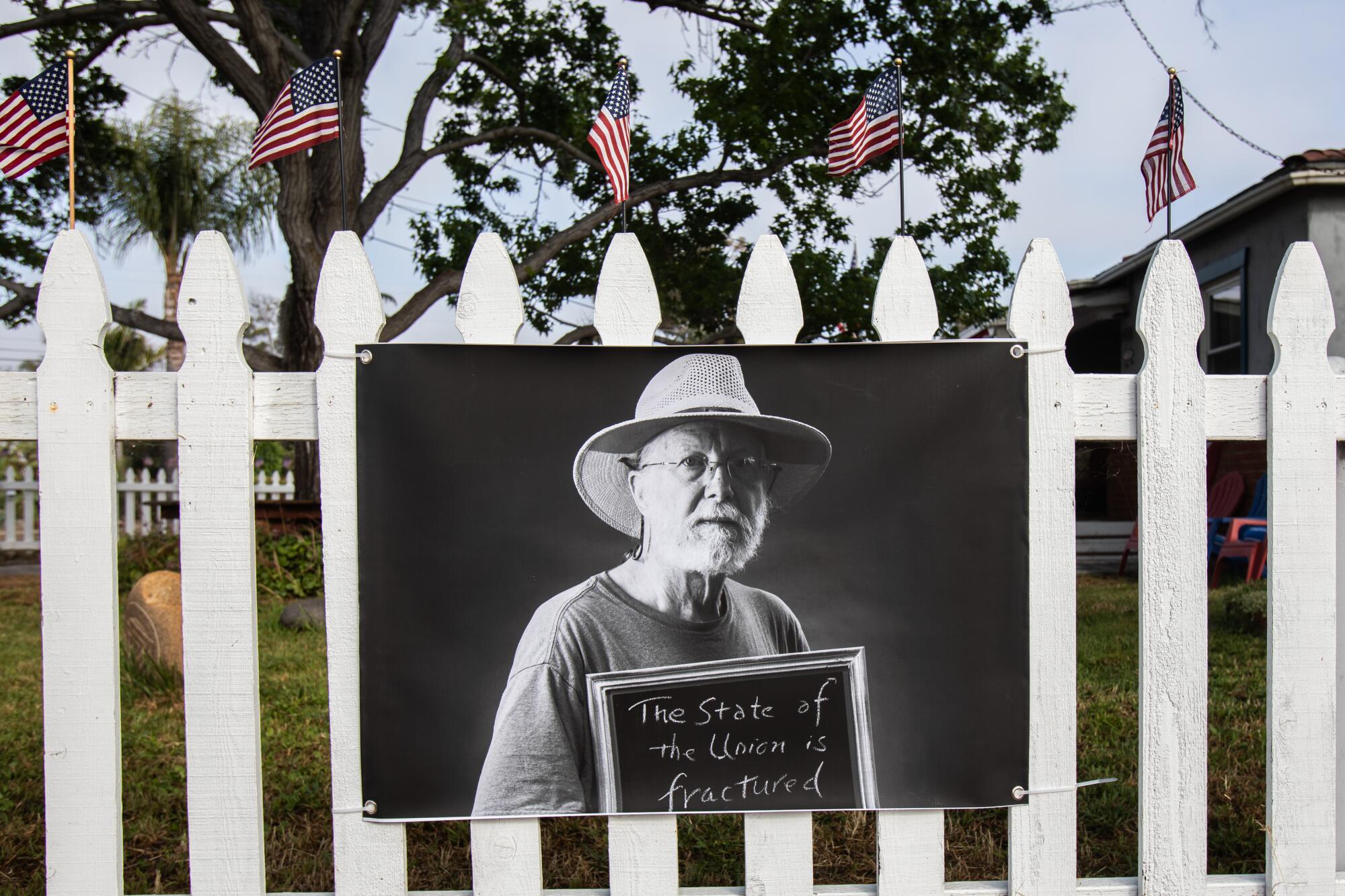 A black and white portrait of a man is hung on a fence 
