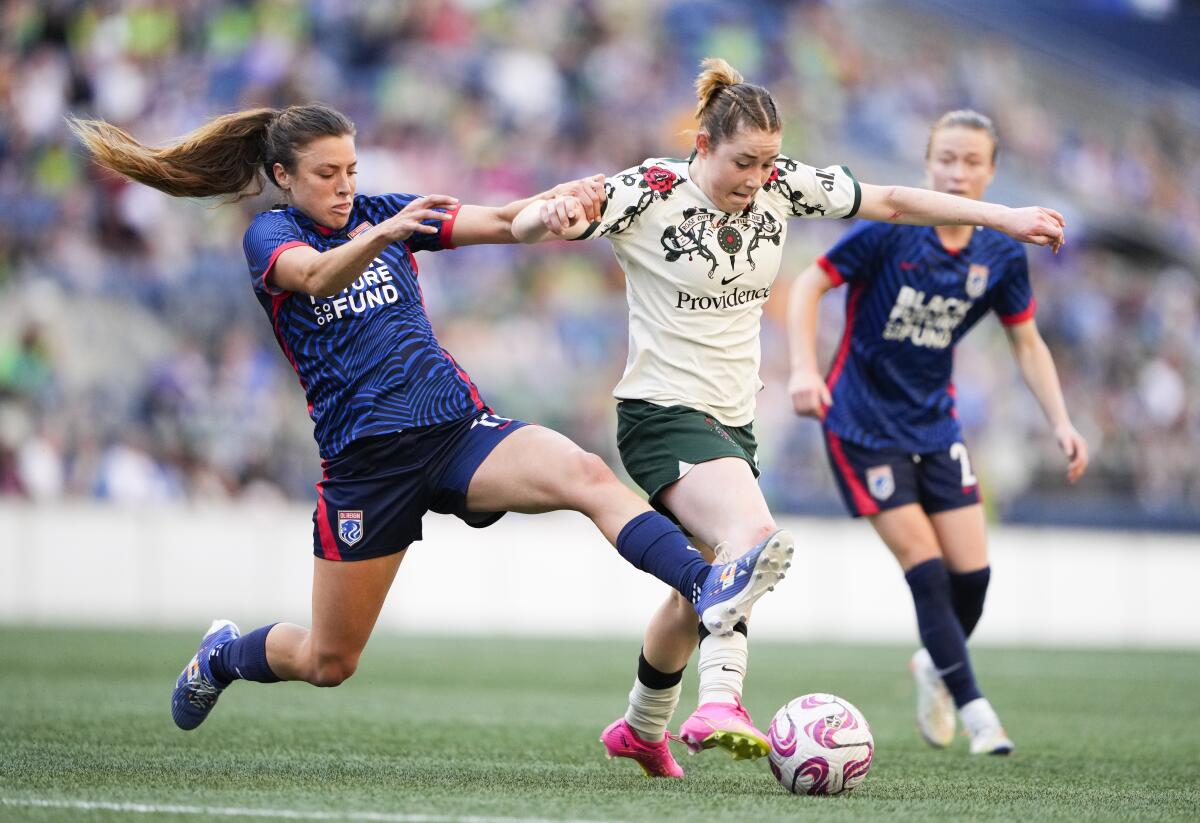 Thorns midfielder Olivia Moultrie is fouled by OL Reign defender Sofia Huerta, left, as she dribbles up the pitch.