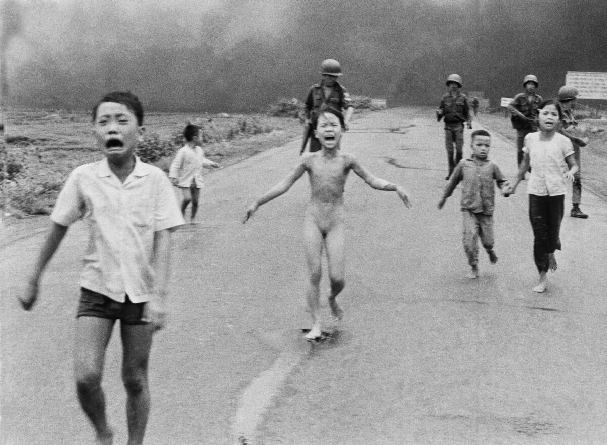 South Vietnamese forces follow terrified children, including 9-year-old Kim Phuc, after an aerial napalm attack. After shooting this photo (for which he won a Pulitzer Prize), Nick Ut took the badly burned girl to a hospital.