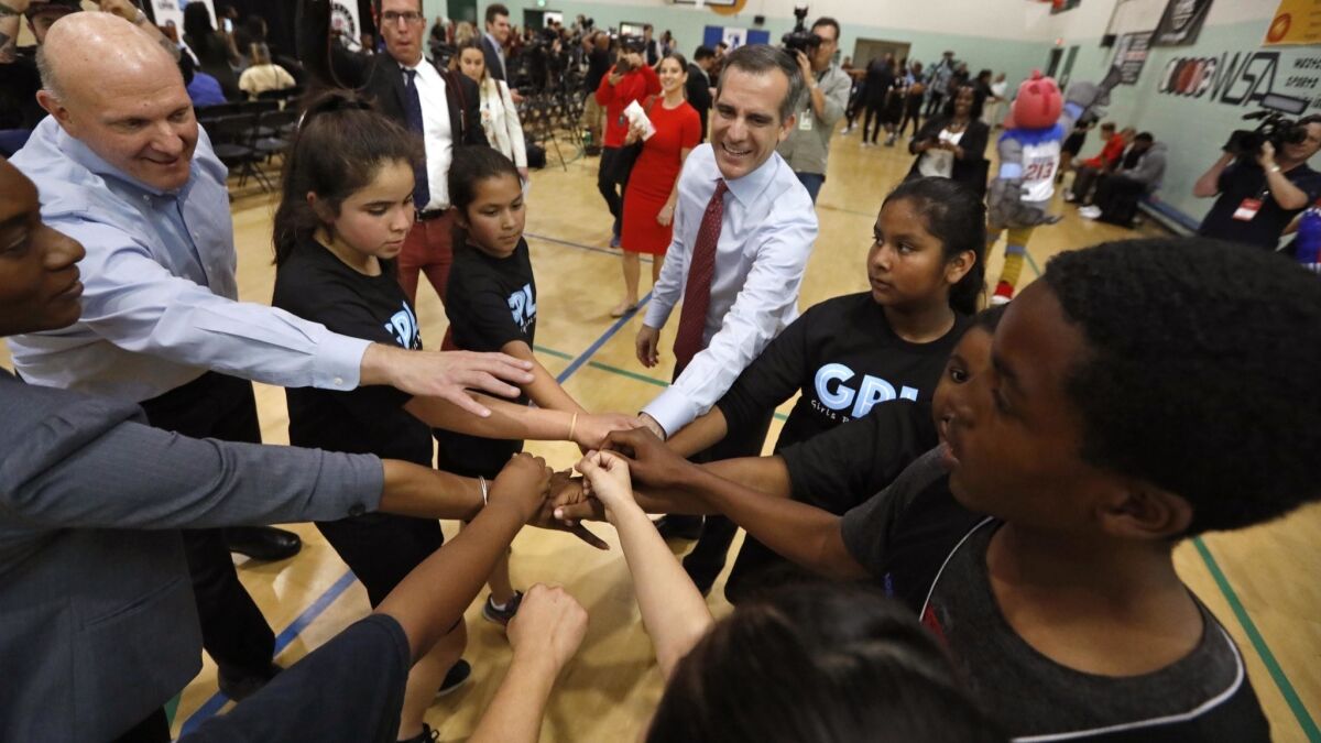 Los Angeles Mayor Eric Garcetti, center, and L.A. Clippers Chairman Steve Ballmer, left, join youngsters with the Junior Clippers and Girls Play Los Angeles for a cheer before the announcement of a $10-million donation by the Clippers Foundation.