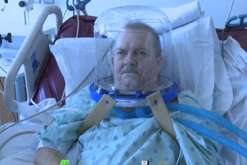 A patient wearing a helmet-based ventilation device.