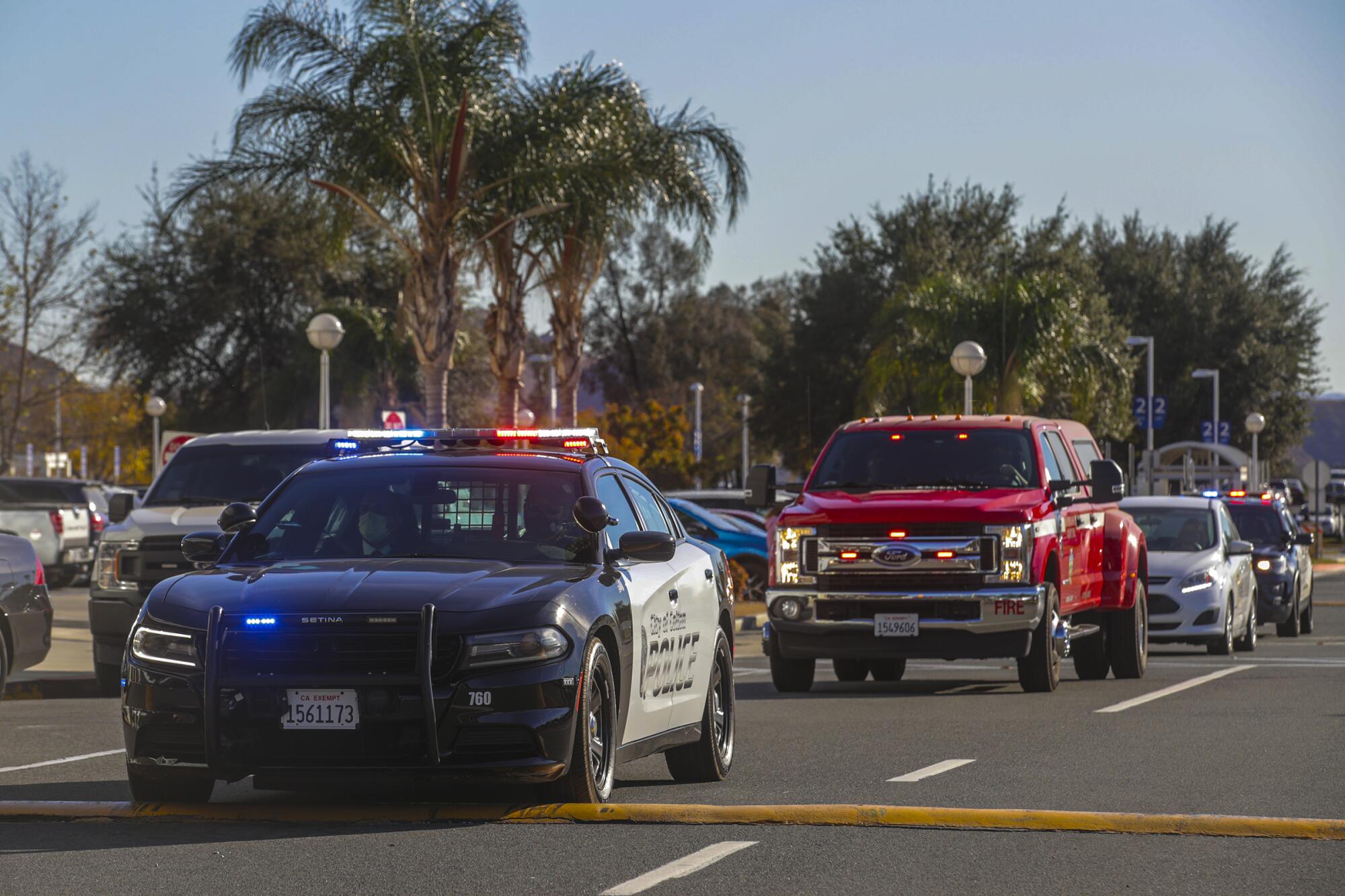 Escorting police cars bookend a fire department pickup truck carrying vaccine doses