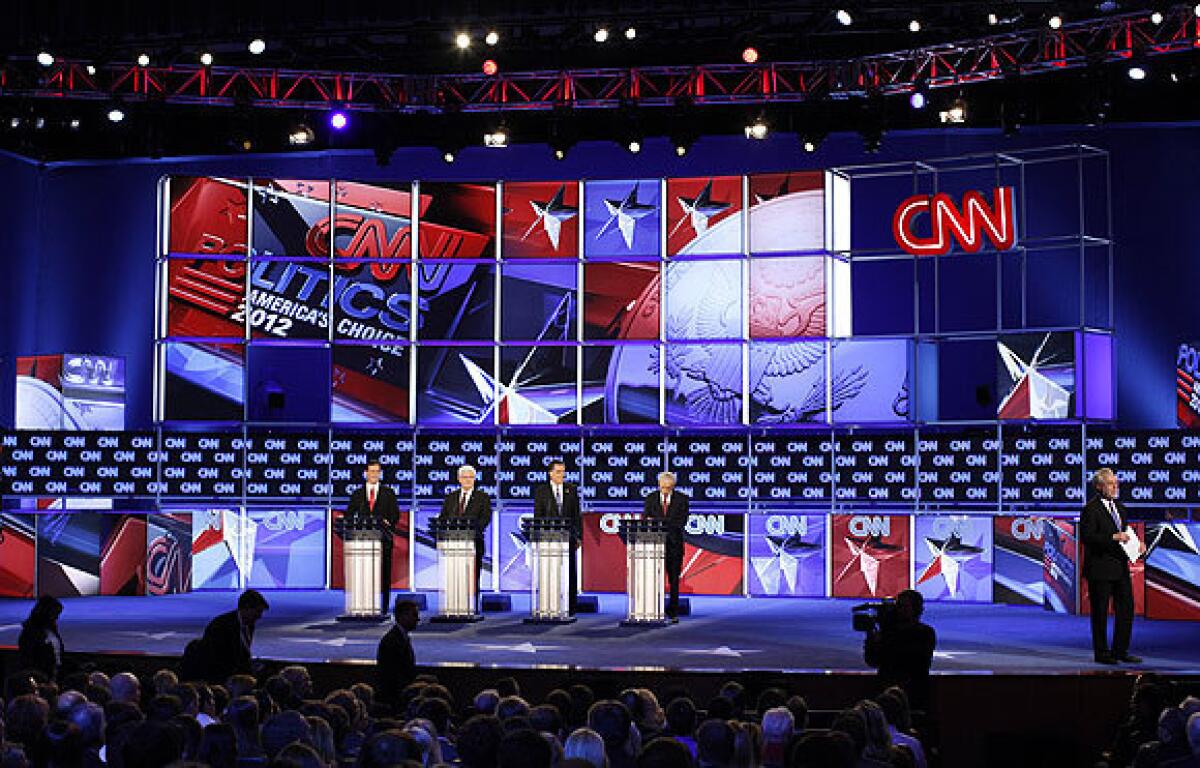 CNN's Wolf Blitzer is seen at right as Republican presidential candidates, from left, former Pennsylvania Sen. Rick Santorum, former House Speaker Newt Gingrich, former Massachusetts Gov. Mitt Romney and Rep. Ron Paul of Texas participate in the debate in Jacksonville, Fla.