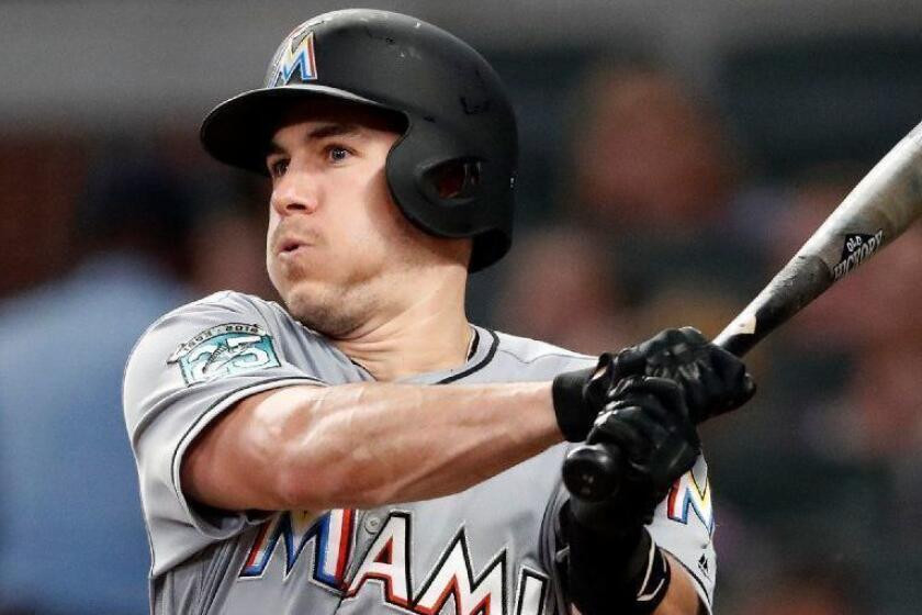 FILE - In this Tuesday, Aug. 14, 2018 file photo, Miami Marlins' J.T. Realmuto follows through on two-run base hit in the fourth inning of a baseball game against the Atlanta Braves in Atlanta. A person familiar with the negotiations says Miami Marlins All-Star catcher J.T. Realmuto has been traded to the Philadelphia Phillies for catcher Jorge Alfaro, two pitching prospects and international bonus pool allocation. The person confirmed the trade to The Associated Press on condition of anonymity Thursday, Feb. 7, 2019 because the teams had not announced it. (AP Photo/John Bazemore, File)