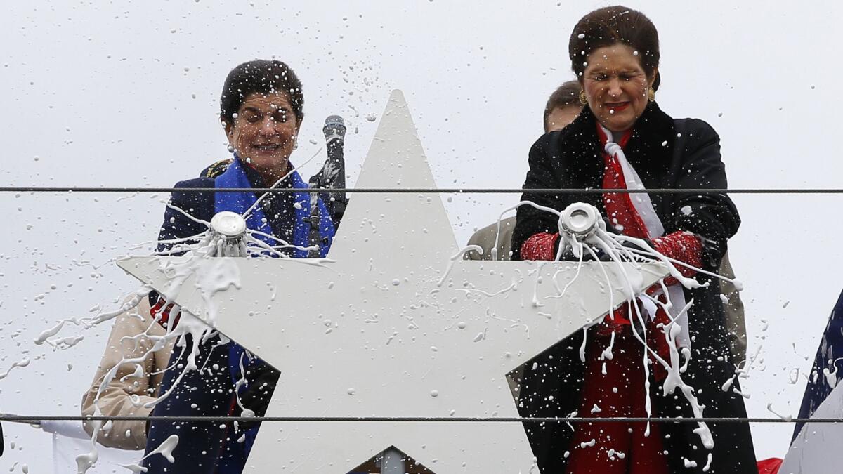 Luci Baines Johnson, left, and her sister, Lynda Bird Johnson Robb, smash Champagne bottles to christen the warship named after their father, President Lyndon B. Johnson.