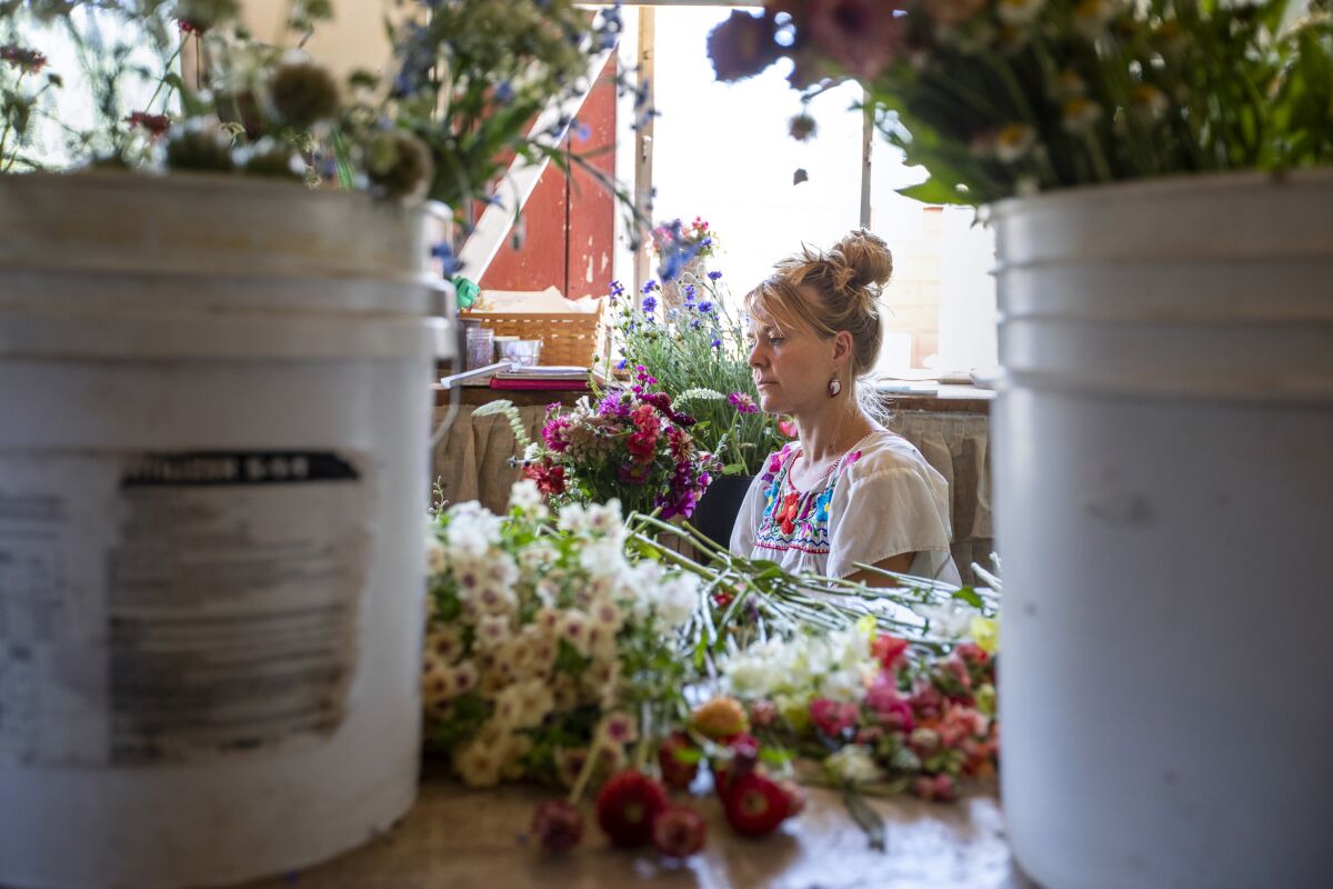 A woman surrounded by flowers inside a shop.