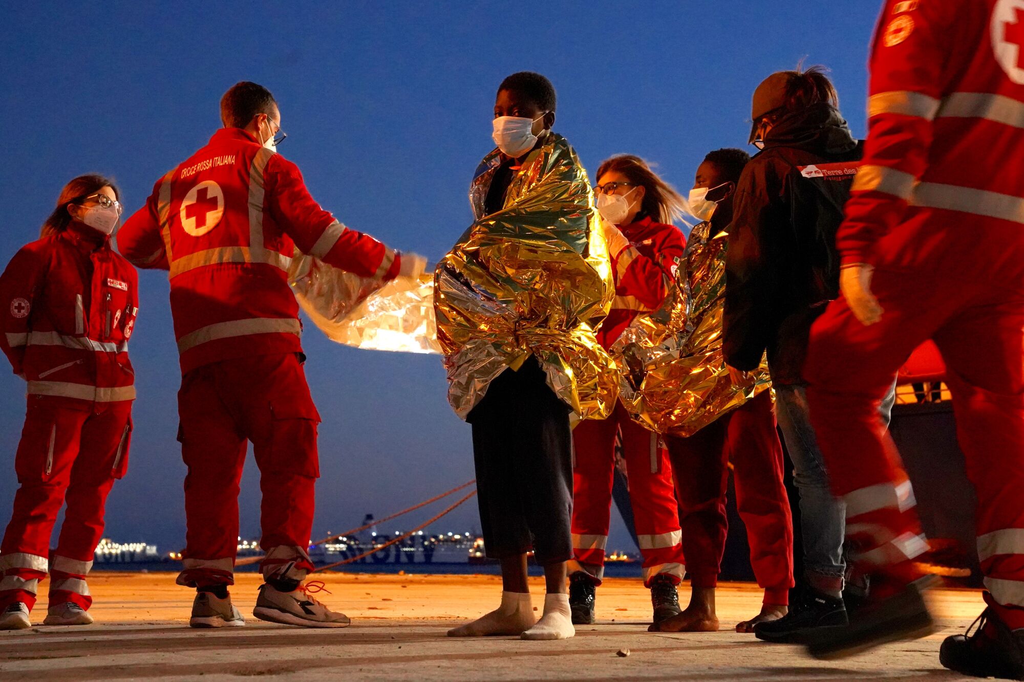 Rescue workers wrap young migrants in reflective blankets