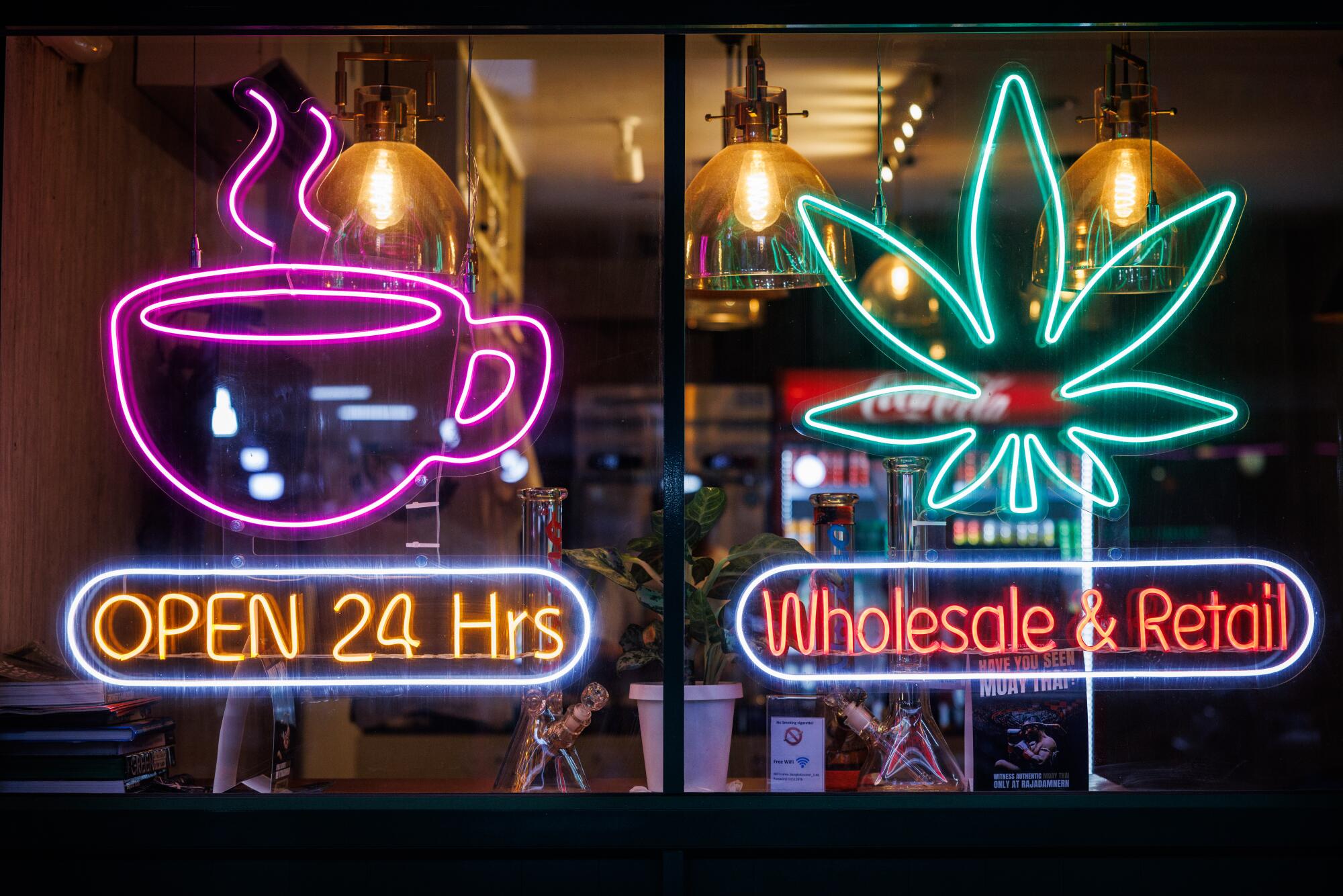 Signs depicting a cup and a marijuana leaf, with the words Open 24 Hrs and Wholesale & Retail