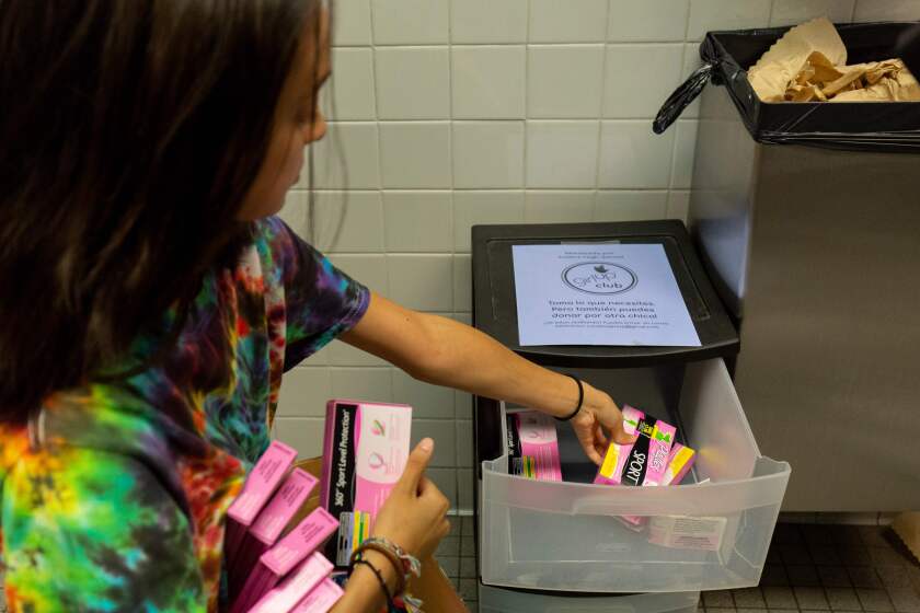 A student of the "Girl Up" club stocks a school bathroom with free pads and tampons to push for menstrual equity, at Justice High School in Falls Church, Virginia.