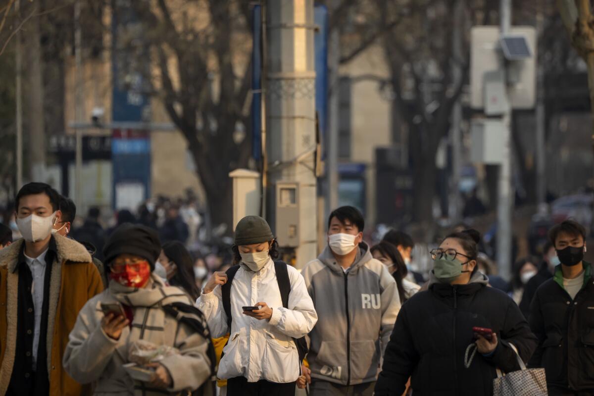 Personas con mascarillas caminan por una calle durante la hora pico matutina en el distrito empresarial en Beijing