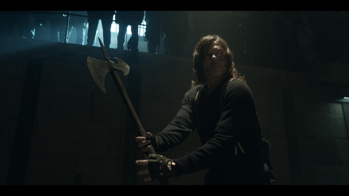 A man wields an axe in a makeshift arena in this shot as it appears on TV in "The Walking Dead: Daryl Dixon."