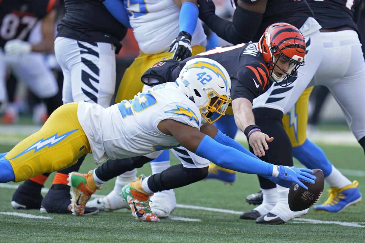 The Chargers' Uchenna Nwosu (42) and the Bengals' Joe Burrow dive for the quarterback's fumble. Nwosu recovered.