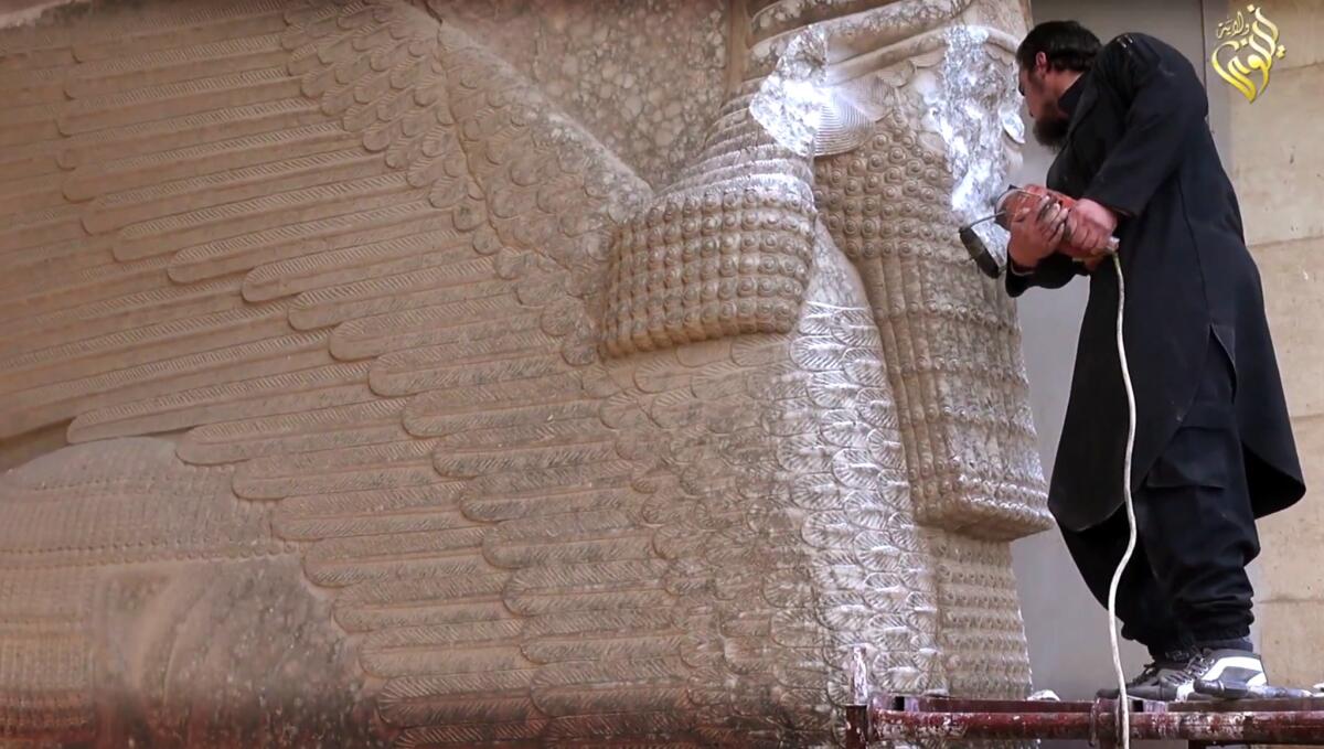 A militant uses a power tool to destroy a winged-bull, an Assyrian protective deity, at the Nineveh Museum in Mosul, Iraq.