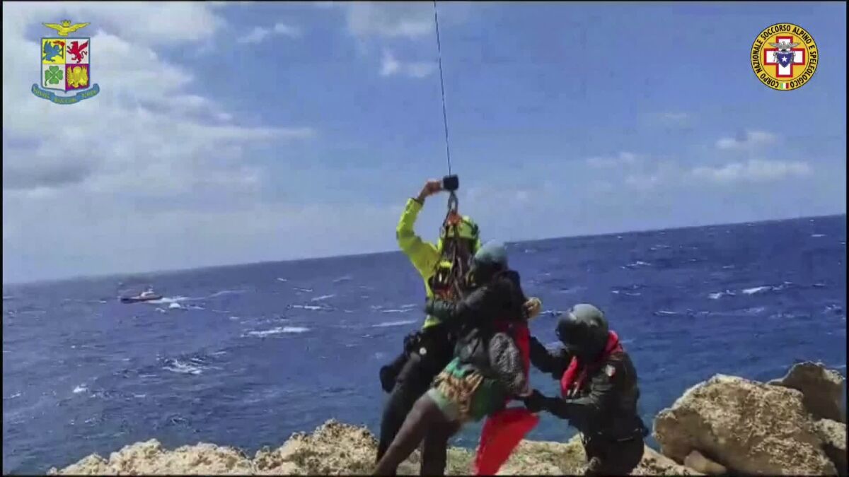 In this picture taken from video distributed on Sunday, Aug. 6, 2023 by the Italian Alpine Rescue squads, a migrant stranded on a rocky reef on the tiny Italian southern island of Lampedusa, Sicily is pluck to safety by helicopter. Dozens of migrants were dramatically rescued by Italy as they foundered in the sea or clung to a rocky reef Sunday after three boats launched by smugglers from northern Africa shipwrecked in rough waters in separate incidents over the weekend (Italian Alpine Rescue via AP)
