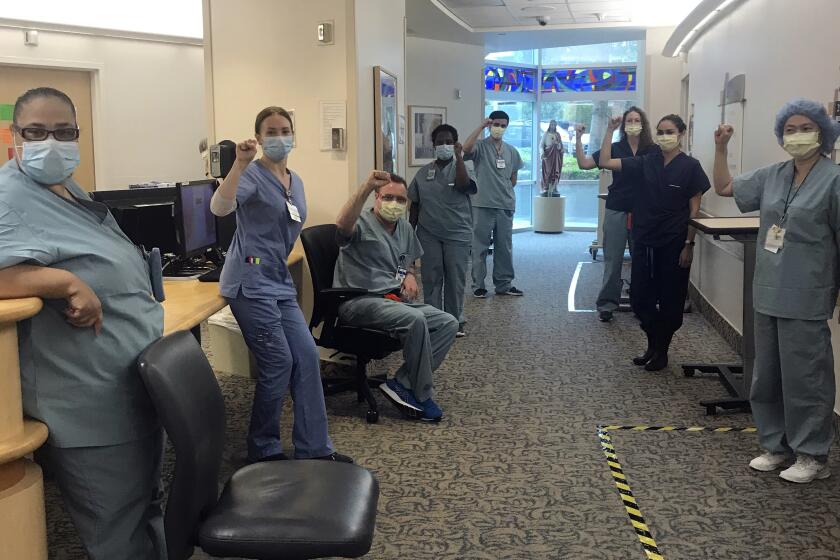 In this image provided by Lizabeth Baker Wade, nurses at Providence Saint John's Health Center in Santa Monica, Calif., on April 10, 2020, raise their fists in solidarity after telling managers they can't care for COVID-19 patients without N95 respirator masks to protect themselves. The hospital has suspended ten nurses from the ward, but has started providing nurses caring for COVID-19 patients with N95 masks. (Lizabeth Baker Wade via AP)