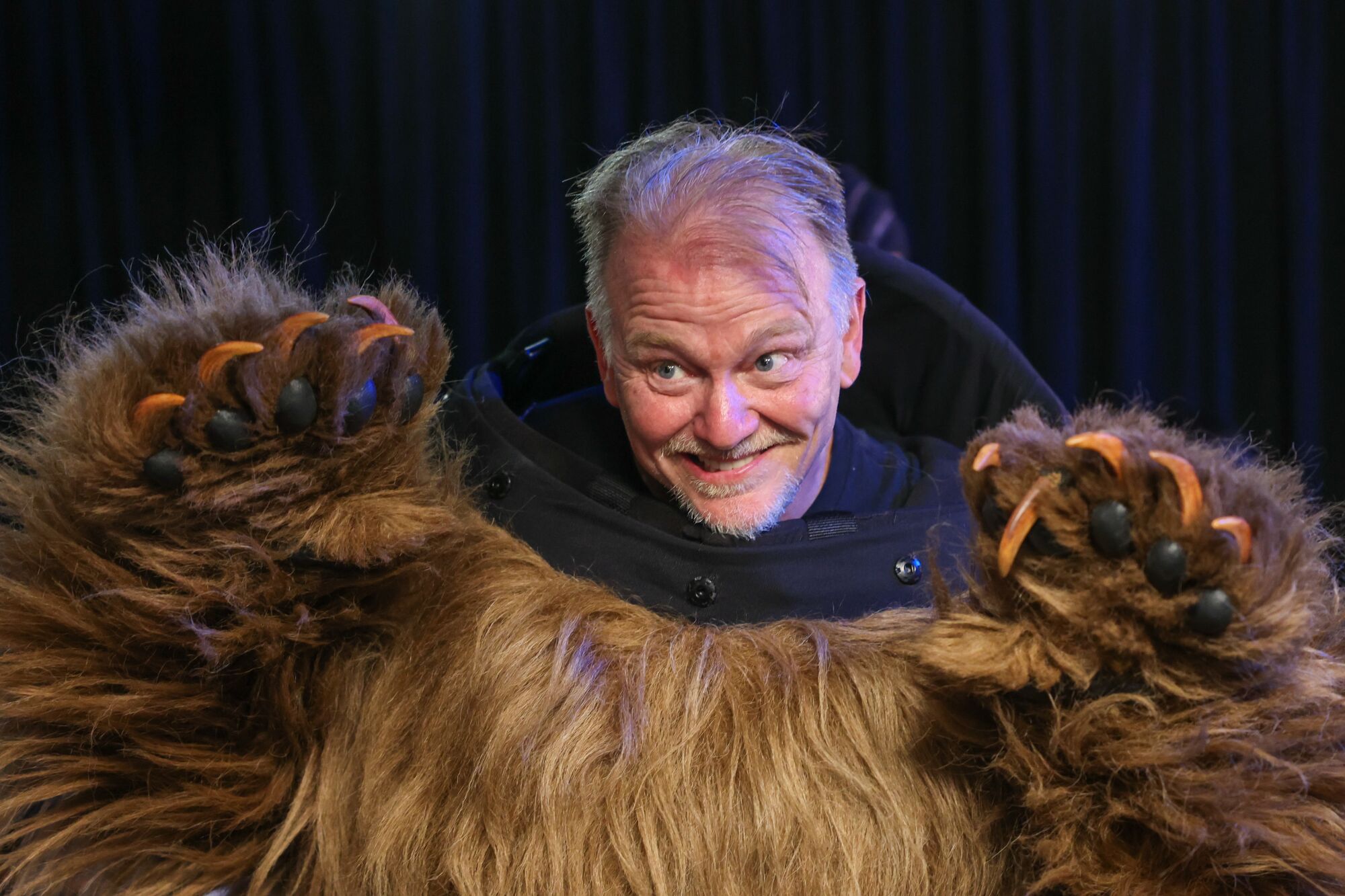 A man in a bear costume reveals his own head.