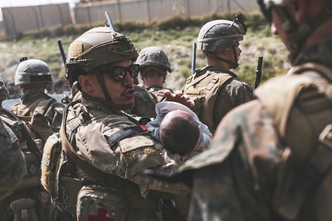 تفنگداران آمریکایی در هنگام تخلیه در فرودگاه بین المللی حامد کرزی در کابل ، افغانستان نوزاد را آرام می کنند