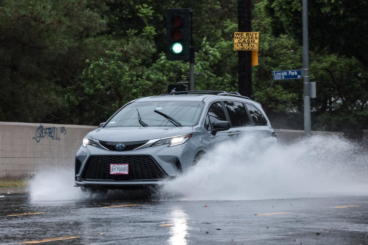 A car drives through a flooded street. 