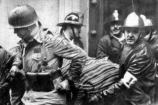 FILE - Soldiers and firefighters carry the body of Chile's President Salvador Allende, wrapped in a Bolivian poncho, out the destroyed presidential palace of La Moneda after the Sept. 11, 1973 coup led by Gen. Augusto Pinochet the ended Allende's three-year government. Chilean judicial officials vowed Thursday, Jan. 27, 2011 to investigate the death of Allende, 37 years after he was found shot through the head with a machine gun during an attack on the presidential palace. The socialist leader died during the Sept. 11, 1973 coup led by Gen. Augusto Pinochet. (AP Photo/El Mercurio, file)