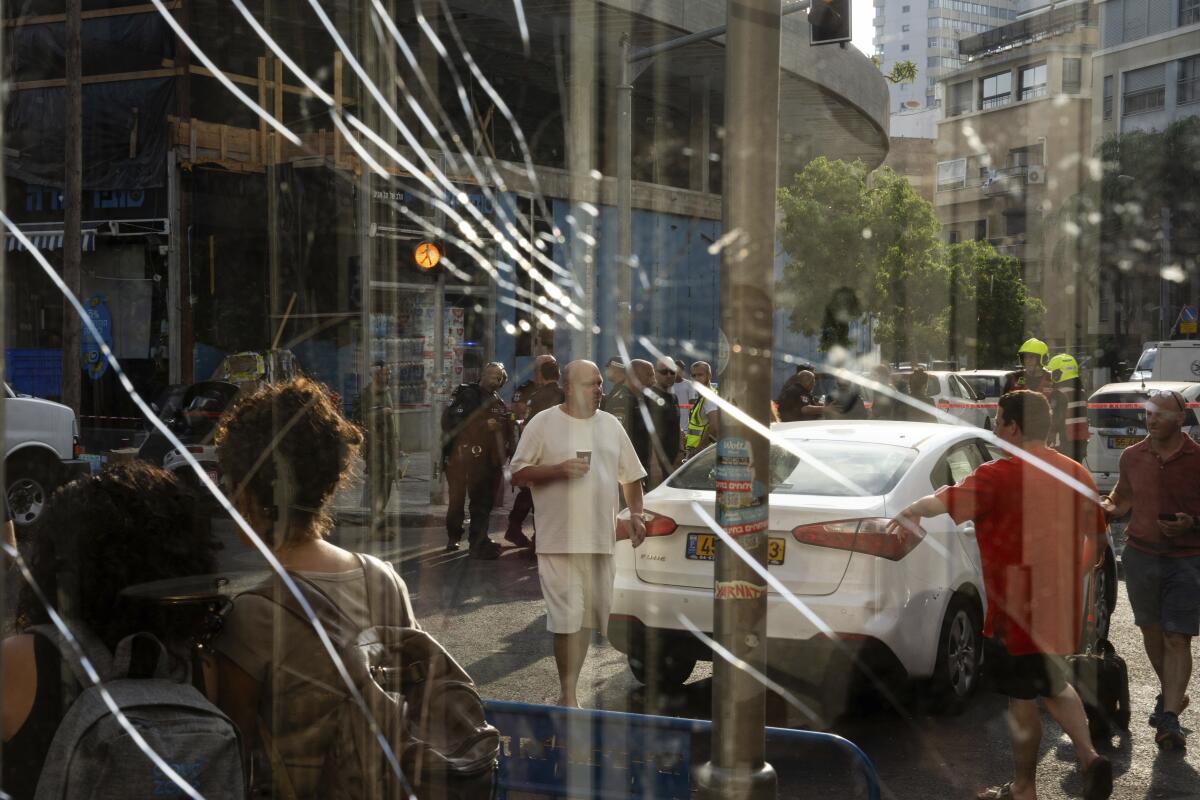 People are seen on the street through a broken window.