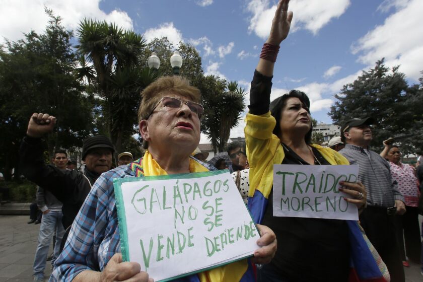 A woman holds a sign with a message that reads in Spanish; Galapagos is not to be sold, but to be defended, during a protest against the governments plan to allow the U.S. military to use a Galapagos island for aircraft on anti-drug trafficking flights, outside the government palace in Quito, Ecuador, Monday, June 17, 2019. Protesters say the plan was a threat to the environment of the U.N. world heritage site as well as Ecuadors sovereignty. (AP Photo/Dolores Ochoa)
