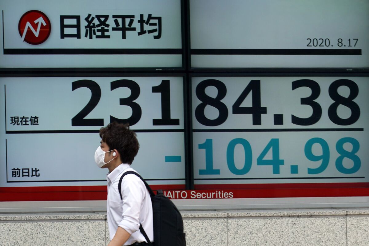 A man walks past an electronic stock board showing Japan's Nikkei 225 index at a securities firm in Tokyo Monday, Aug. 17, 2020. Japanese stocks sank while other Asian markets gained Monday after Japan reported a record economic contraction as the coronavirus pandemic weighed on retailing, investment and exports. (AP Photo/Eugene Hoshiko)