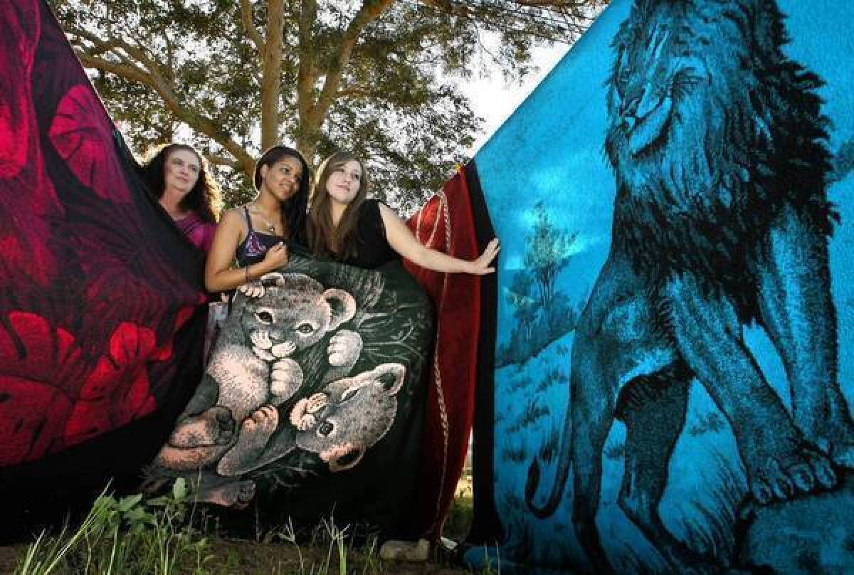 Paula Valenzuela, left, and daughters Elizabeth, middle, and Mariana show off some of the family's collection of San Marcos blankets in El Centro.
