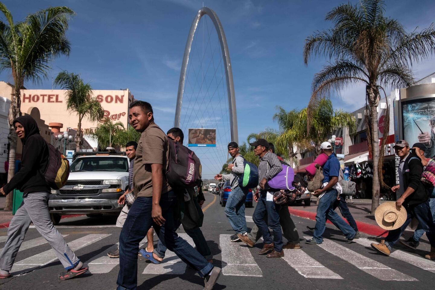 Un grupo de migrantes de países centroamericanos, en su mayoría hondureños, que se dirigen a Estados Unidos con la esperanza de una vida mejor, cruzan una calle en Tijuana, México.