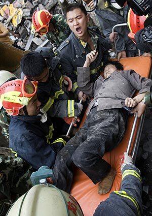 Rescue workers in Dujiangyan, China, carry a woman who survived after being buried for two days under the remains of an apartment building.