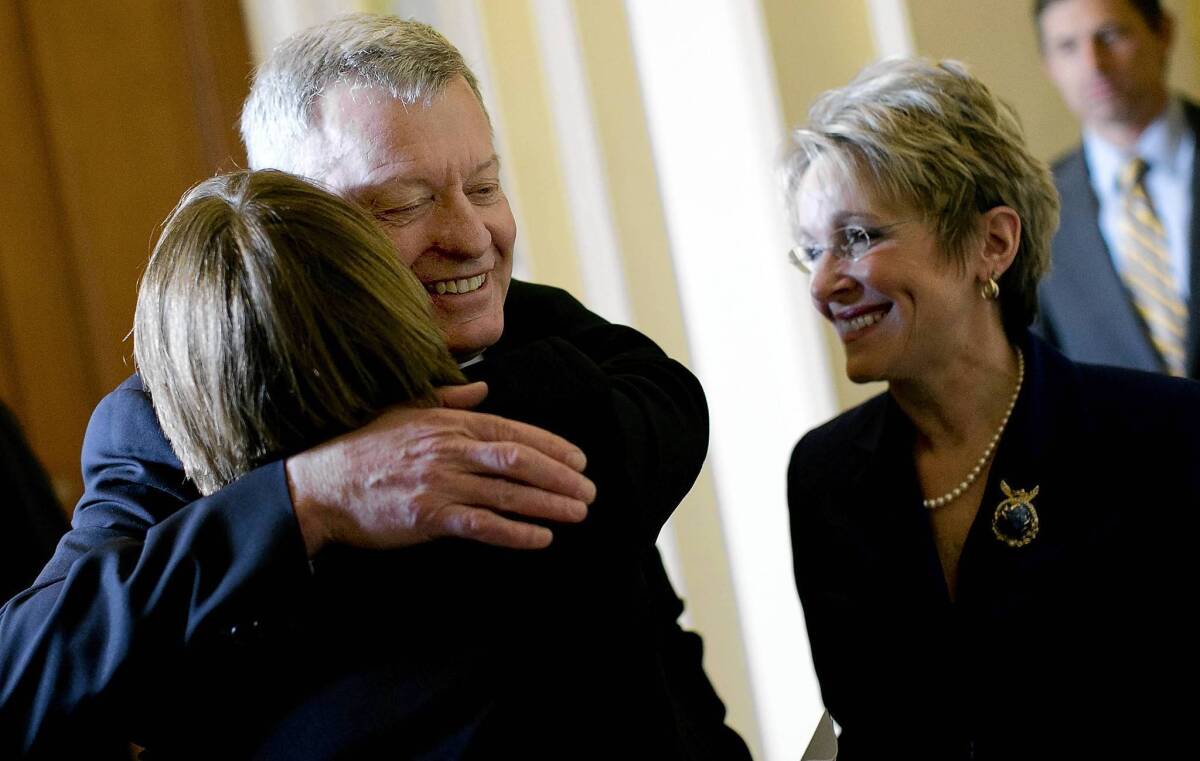 Sen. Amy Klobuchar (D-Minn.) hugs Sen. Max Baucus after the Montana Democrat's announcement that he will not seek reelection next year. At right is his wife, Melodee Hanes.