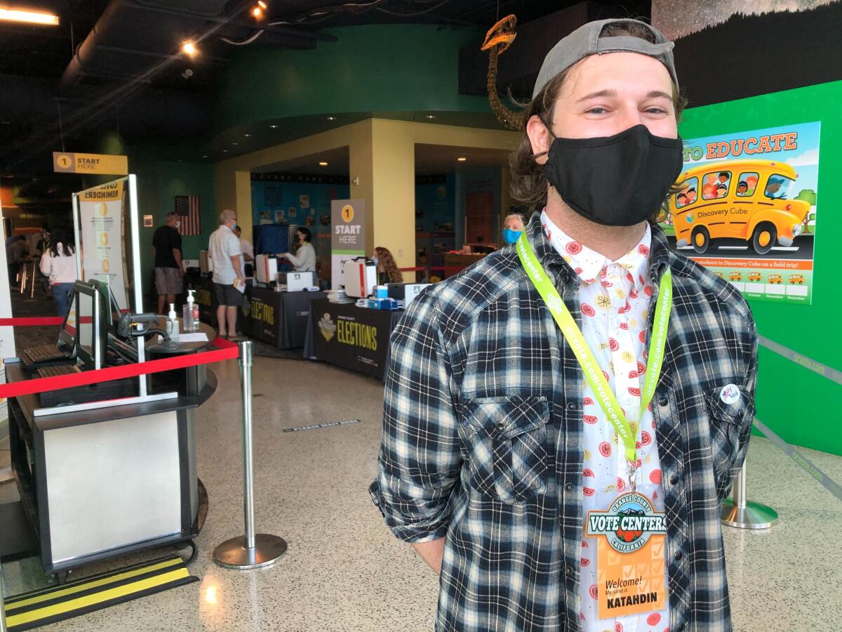 Katahdin Rendino, in black face mask, stands inside the Santa Ana museum and polling site.