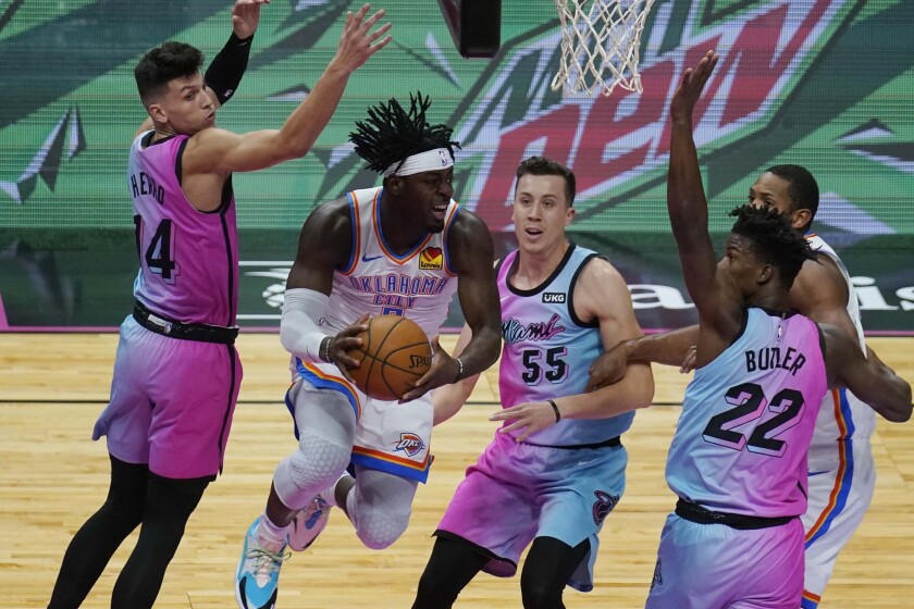Oklahoma City Thunder guard Luguentz Dort (5) grabs a rebound surrounded by Miami Heat forward Duncan Robinson (55), forward Jimmy Butler (22) and guard Tyler Herro (14), during the first half of an NBA basketball game, Monday, Jan. 4, 2021, in Miami. (AP Photo/Marta Lavandier)