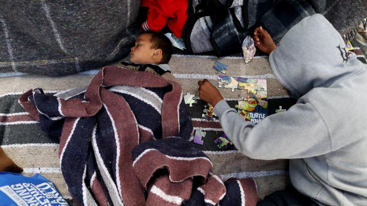 Gustavo Guinak, 2, and brother Wilson Guinak of Guatemala, along with other Central Americans, wait for an appointment for asylum at an encampment near the El Chaparral Port of Entry in Tijuana, Baja Calif., on May 1.