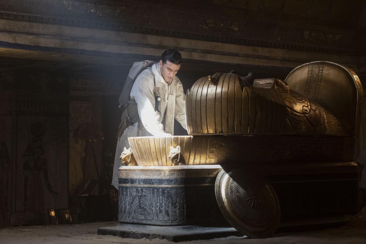 A man opens a sarcophagus illuminated by a ray of light