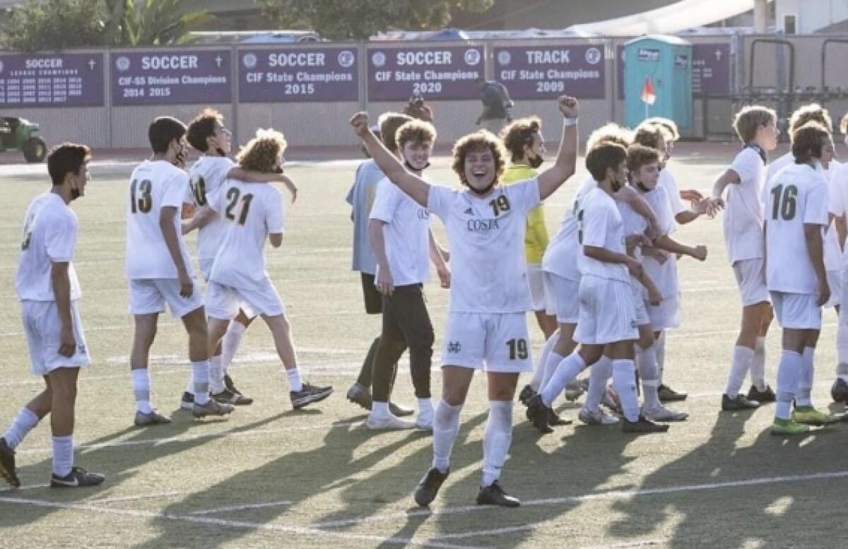 Mira Costa's Thomas Southey holds his hands up while teammates walk behind him across a field.