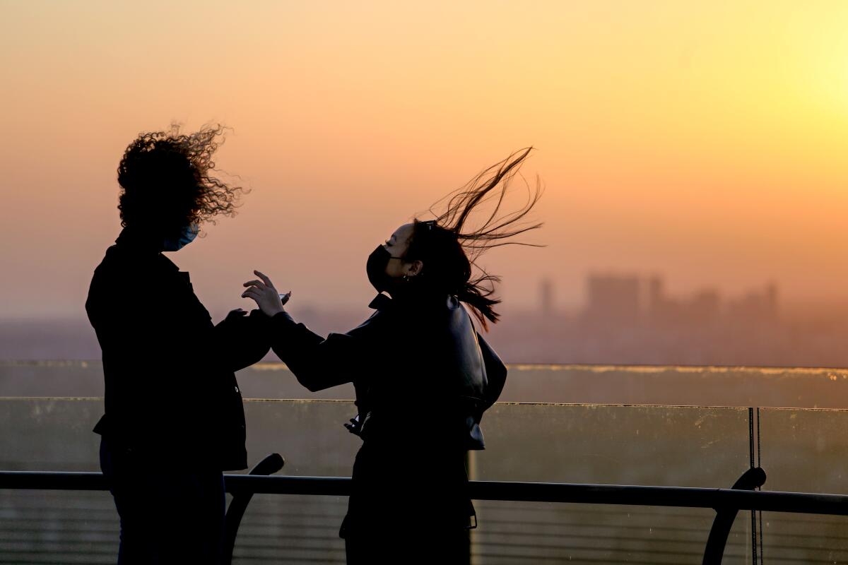 Santa Ana winds whip the hair of two people at Griffith Observatory in January.