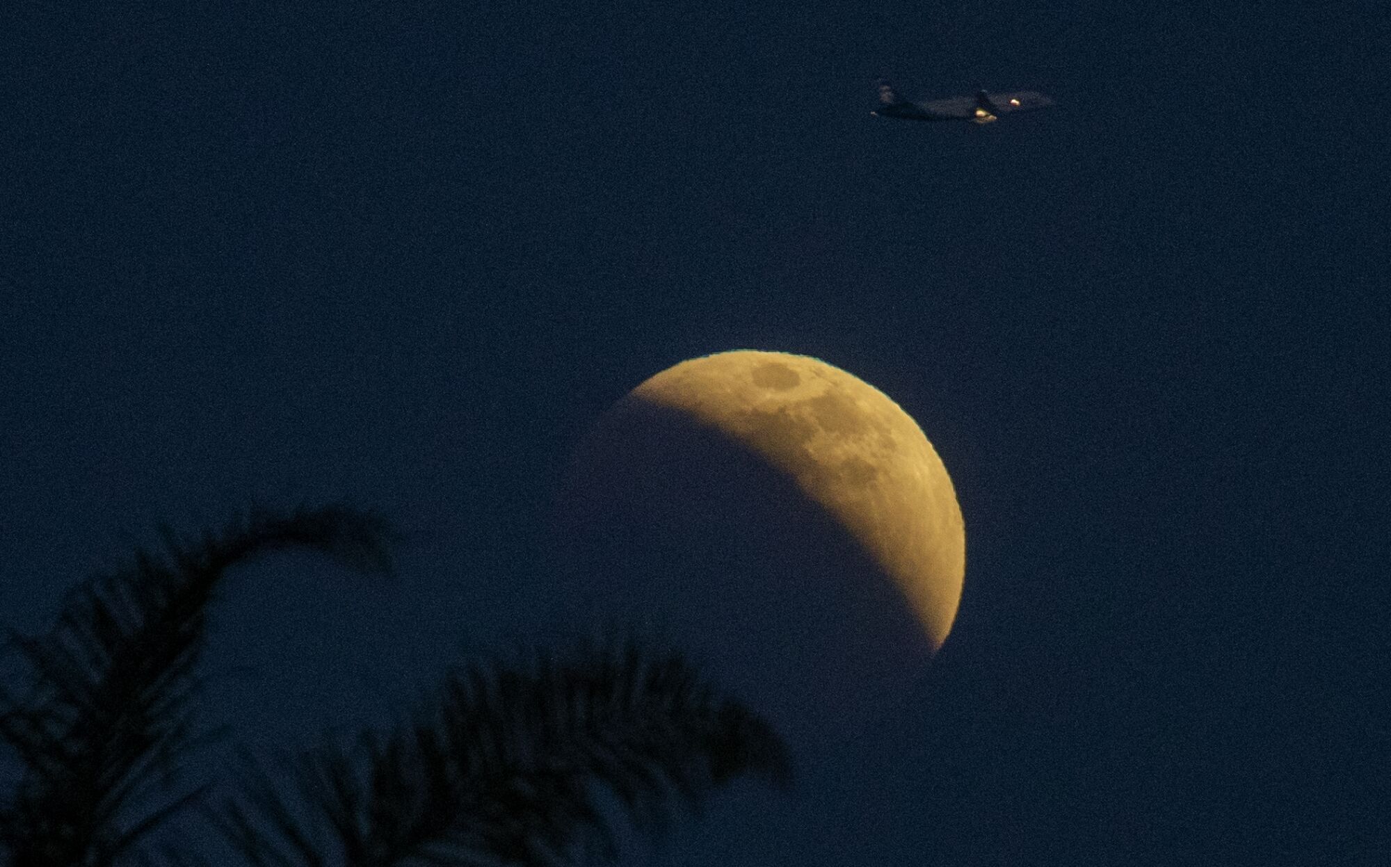 An eclipsing moon with a plane flying by