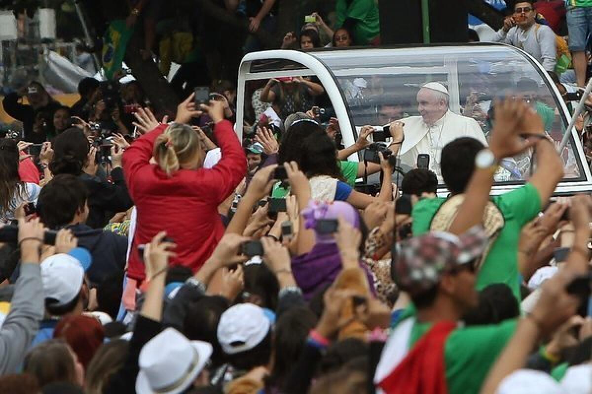 Pope Francis is mobbed by young pilgrims upon his arrival to Copacabana beach in Rio de Janeiro.